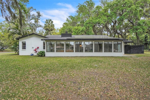 back of house with a yard, a chimney, and a sunroom