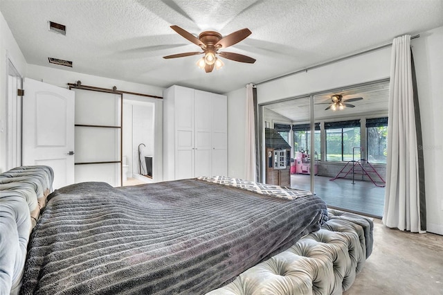 bedroom with access to exterior, a barn door, a textured ceiling, ceiling fan, and concrete floors