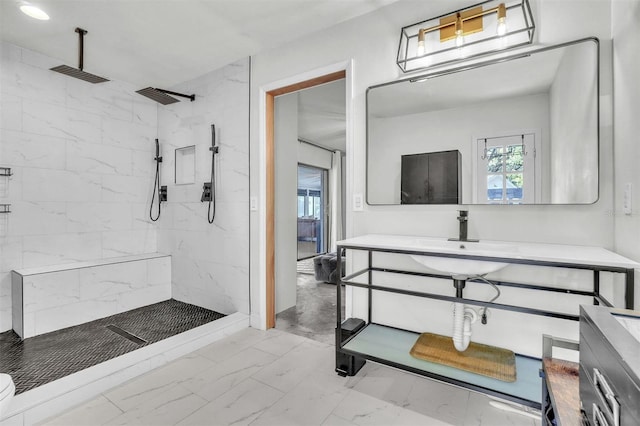 full bathroom with marble finish floors, a tile shower, and vanity