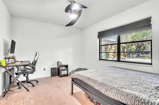 bedroom with light wood-type flooring, a desk, baseboards, and ceiling fan