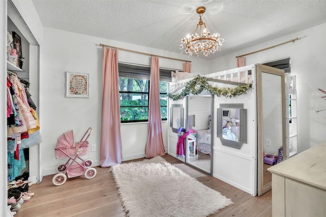 dining space featuring a chandelier, light wood-type flooring, a textured ceiling, and baseboards