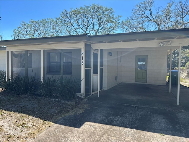 exterior space with an attached carport, concrete block siding, and driveway