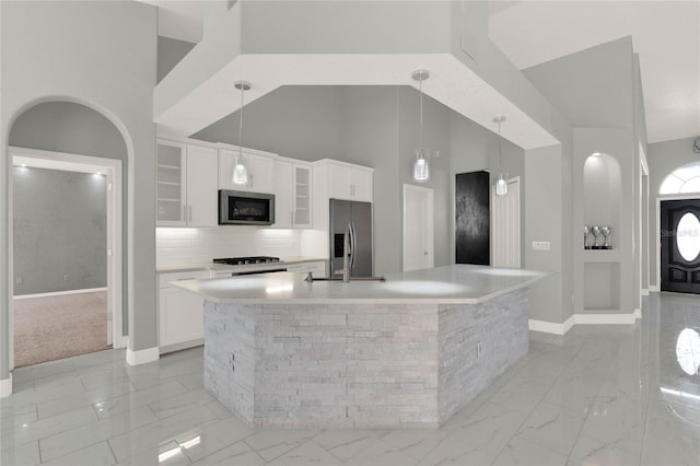 kitchen featuring marble finish floor, a high ceiling, white cabinetry, and stainless steel appliances