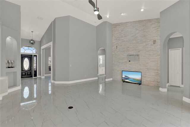 foyer entrance featuring arched walkways, marble finish floor, a towering ceiling, and baseboards