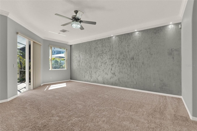 empty room featuring ceiling fan, carpet flooring, visible vents, baseboards, and ornamental molding