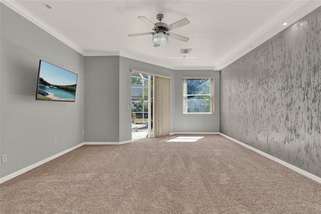 carpeted spare room with ornamental molding, a ceiling fan, and baseboards