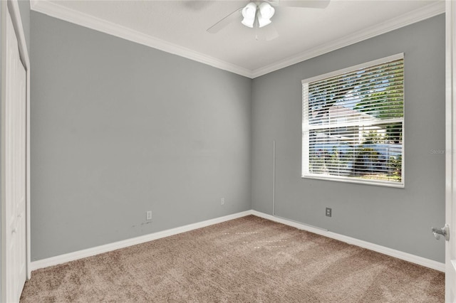 carpeted spare room featuring baseboards, ceiling fan, and crown molding