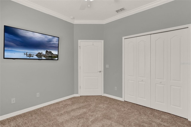 unfurnished bedroom with a ceiling fan, baseboards, a closet, carpet, and crown molding