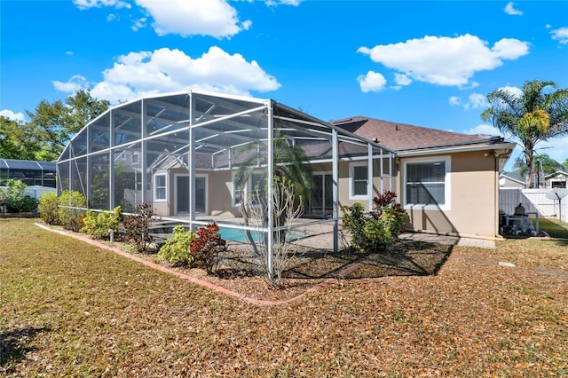 rear view of property with a yard, a patio, stucco siding, fence, and a lanai