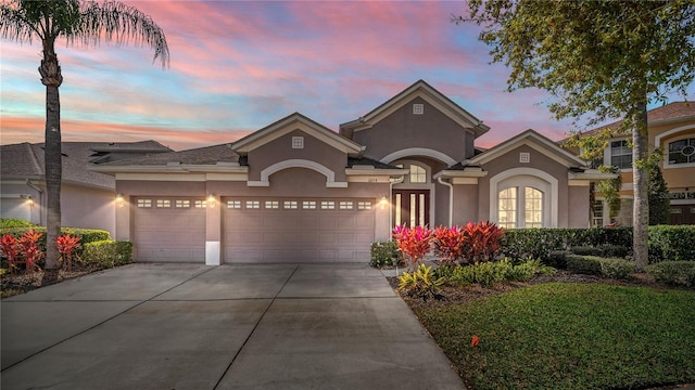 view of front facade featuring an attached garage, driveway, and stucco siding