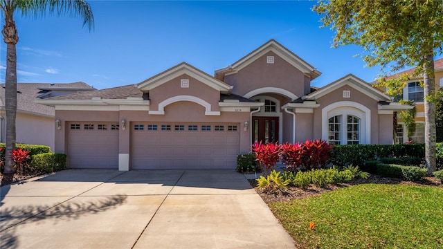 view of front of house featuring a garage, driveway, french doors, and stucco siding