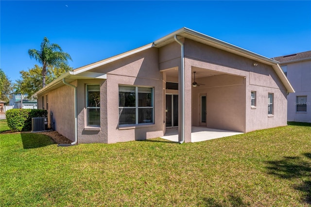 back of property with ceiling fan, a patio, central AC, a lawn, and stucco siding