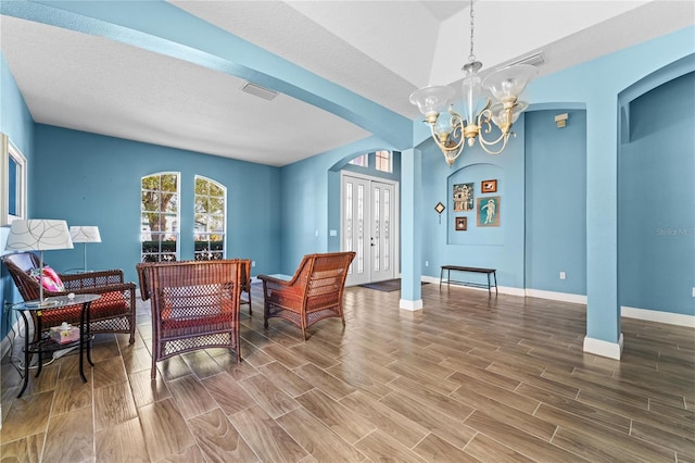 living area with arched walkways, visible vents, wood tiled floor, a chandelier, and baseboards