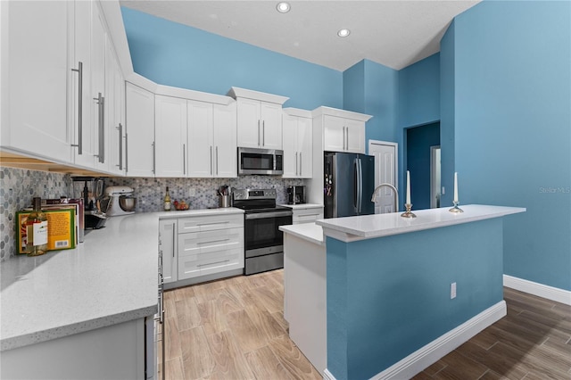 kitchen featuring light wood finished floors, white cabinetry, appliances with stainless steel finishes, and backsplash