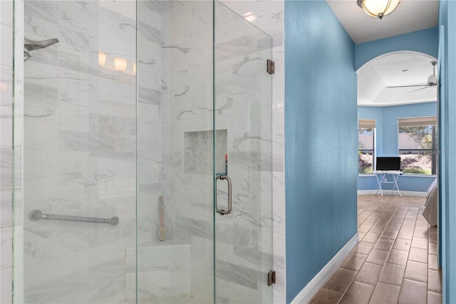 bathroom featuring a stall shower, wood tiled floor, a ceiling fan, and baseboards