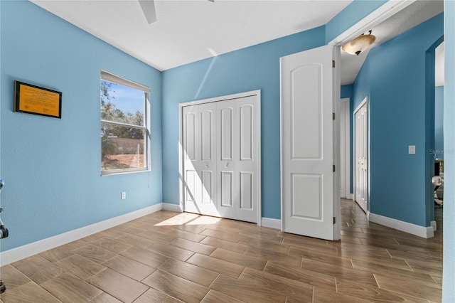 unfurnished bedroom featuring baseboards, a closet, a ceiling fan, and wood tiled floor