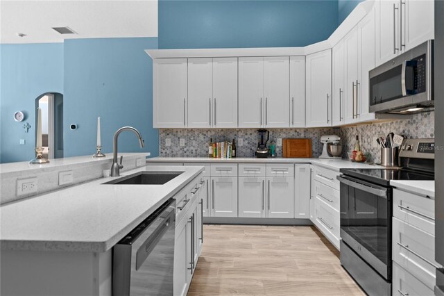 6854 Remington View Ct, Orlando, FL 32829 - kitchen featuring arched walkways, a sink, stainless steel appliances, white cabinets, and tasteful backsplash