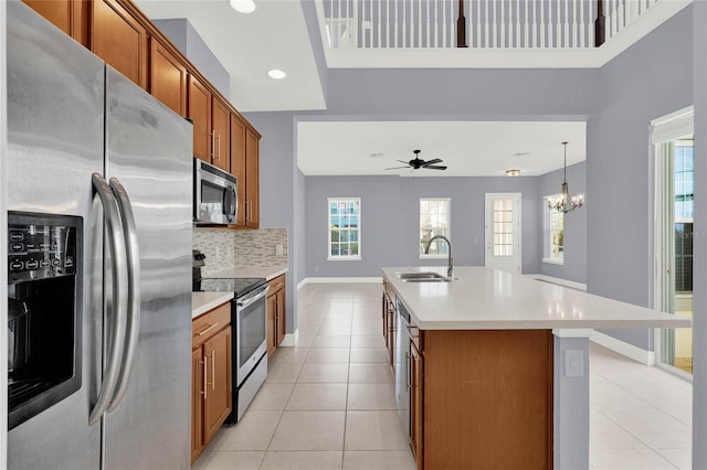 kitchen featuring brown cabinets, a sink, appliances with stainless steel finishes, light countertops, and light tile patterned floors