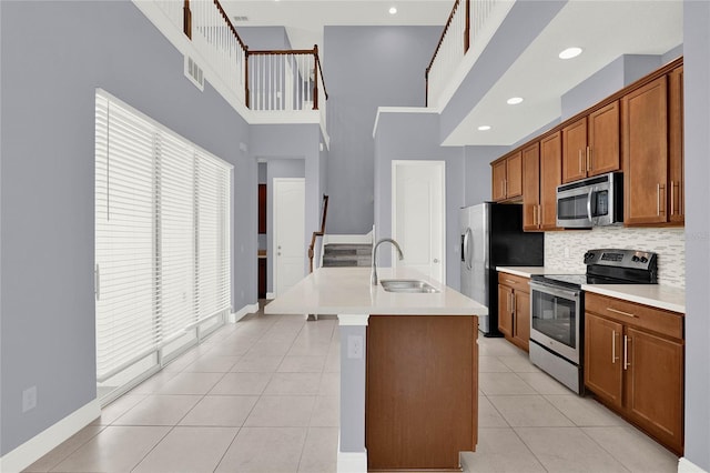 kitchen featuring light tile patterned floors, visible vents, a sink, stainless steel appliances, and brown cabinets