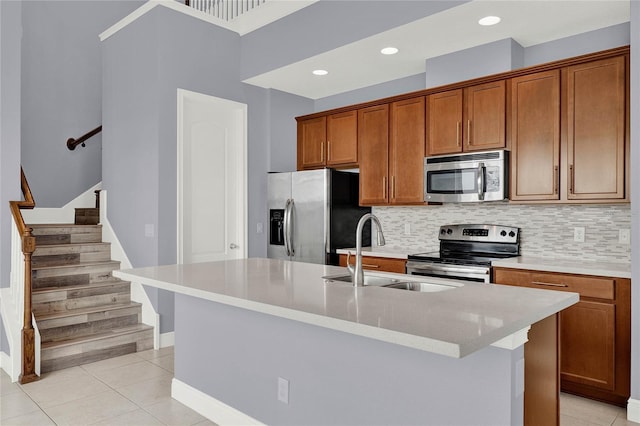 kitchen with a sink, light tile patterned floors, brown cabinetry, and stainless steel appliances