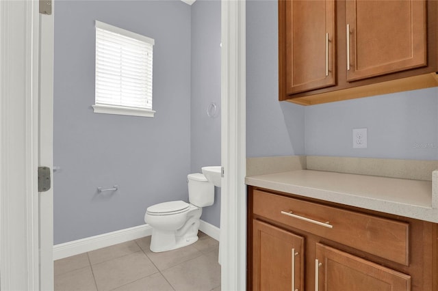 bathroom with baseboards, toilet, and tile patterned flooring