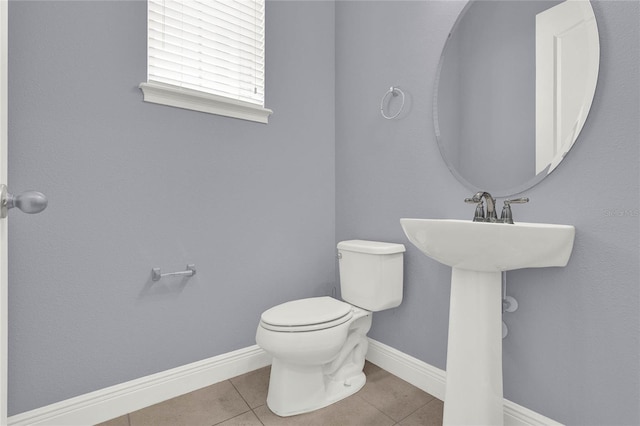 bathroom featuring tile patterned flooring, toilet, baseboards, and a sink