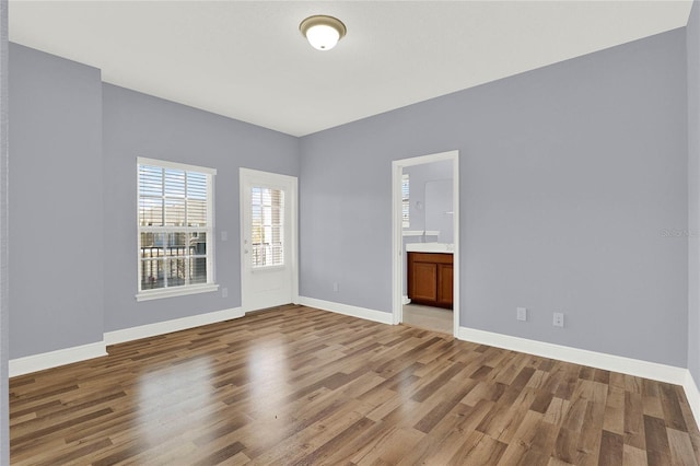 spare room with baseboards and wood finished floors