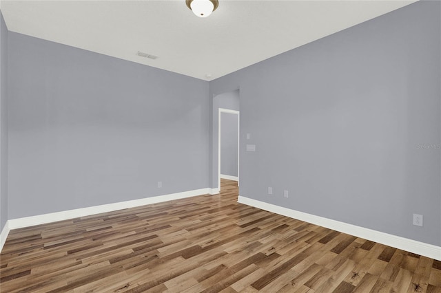 spare room featuring visible vents, baseboards, and wood finished floors