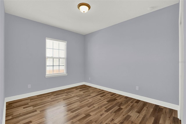 spare room featuring baseboards and wood finished floors