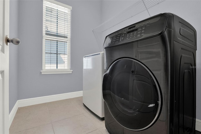 clothes washing area with laundry area, washer / clothes dryer, baseboards, and light tile patterned floors