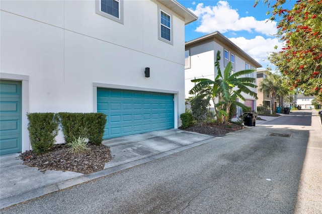 view of side of property with an attached garage, driveway, and stucco siding