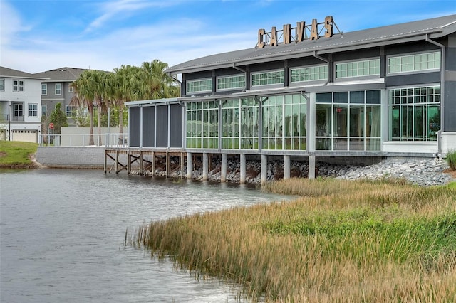 back of property featuring a water view and a sunroom