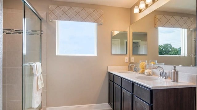 bathroom featuring baseboards, double vanity, a sink, and a shower stall