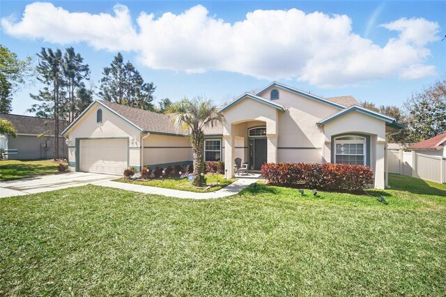 view of front of house with stucco siding, an attached garage, fence, driveway, and a front lawn