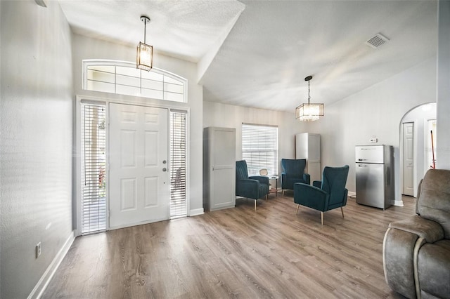 foyer with arched walkways, wood finished floors, visible vents, and baseboards