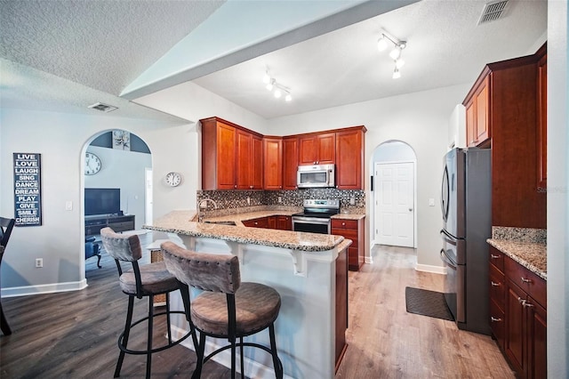 kitchen with tasteful backsplash, visible vents, appliances with stainless steel finishes, a sink, and a peninsula