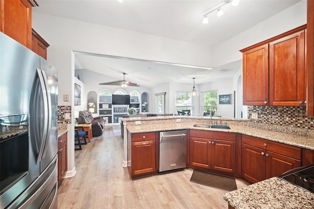 kitchen with arched walkways, light wood-style flooring, a peninsula, a sink, and stainless steel refrigerator with ice dispenser