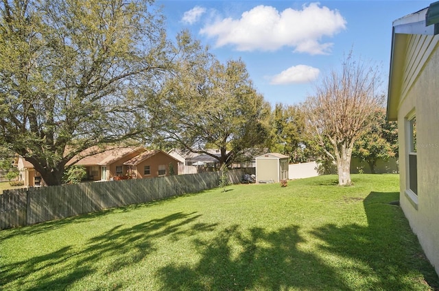 view of yard with a fenced backyard, a shed, and an outbuilding