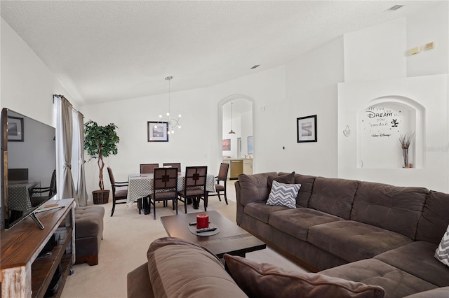 living area featuring visible vents, lofted ceiling, a textured ceiling, a notable chandelier, and light colored carpet