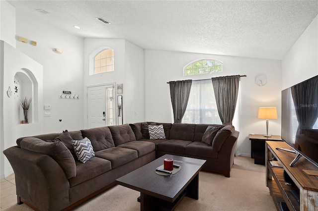 living room featuring light carpet, visible vents, high vaulted ceiling, and a textured ceiling