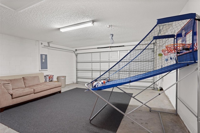 rec room featuring electric panel, a textured ceiling, concrete block wall, a garage, and concrete flooring