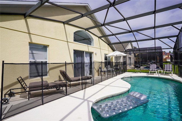 outdoor pool with glass enclosure and a patio