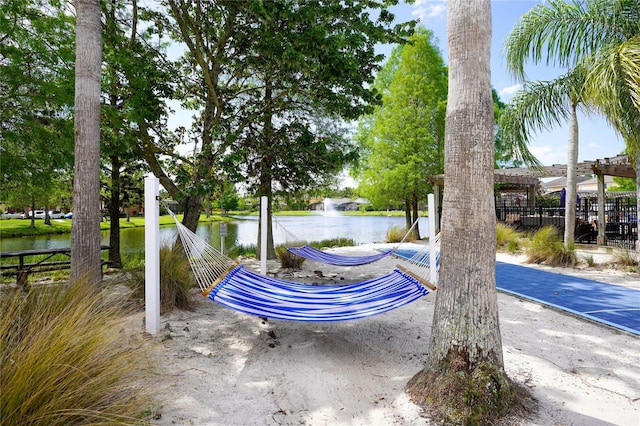 exterior space with a water view, fence, and a pergola