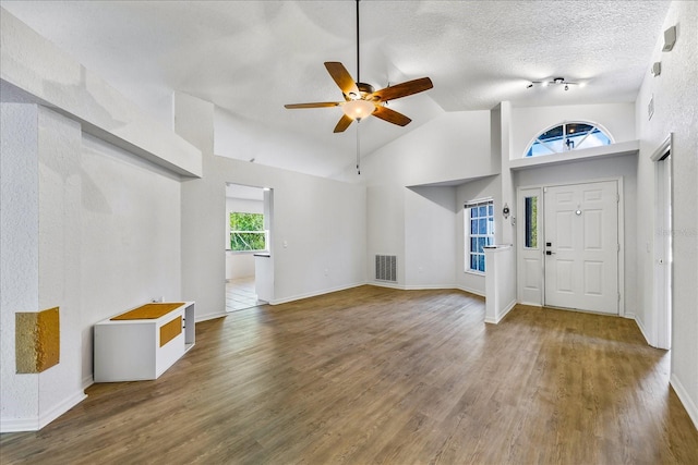 entryway featuring lofted ceiling, visible vents, a textured ceiling, and wood finished floors