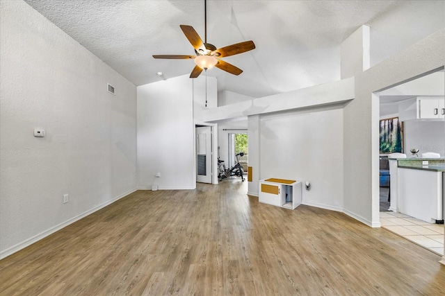 unfurnished living room with lofted ceiling, ceiling fan, visible vents, and light wood-style floors