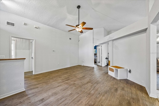 unfurnished living room with a ceiling fan, visible vents, baseboards, and wood finished floors