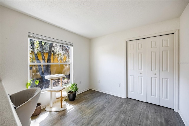 living area with a textured ceiling, wood finished floors, and baseboards