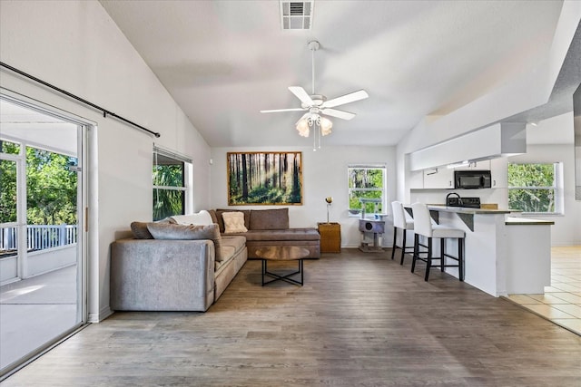 living room featuring vaulted ceiling, ceiling fan, wood finished floors, and visible vents