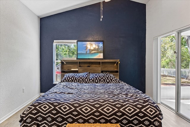 bedroom featuring access to outside, baseboards, wood finished floors, and a textured wall