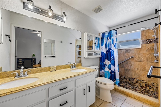 full bathroom with a textured ceiling, visible vents, a tile shower, and a sink